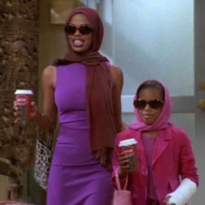black woman wearing sun glasses, scarf around her head and a purple dress. Carrying a coffee cup next to a young black girl matching her.